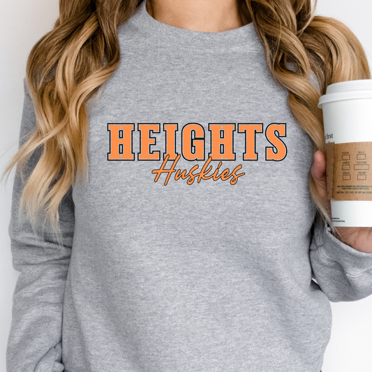 Woman wearing a heather grey Heights Huskies Script Spirit Crewneck Sweatshirt featuring bold orange varsity lettering with Huskies script design in school colors on a comfortable crewneck sweatshirt.