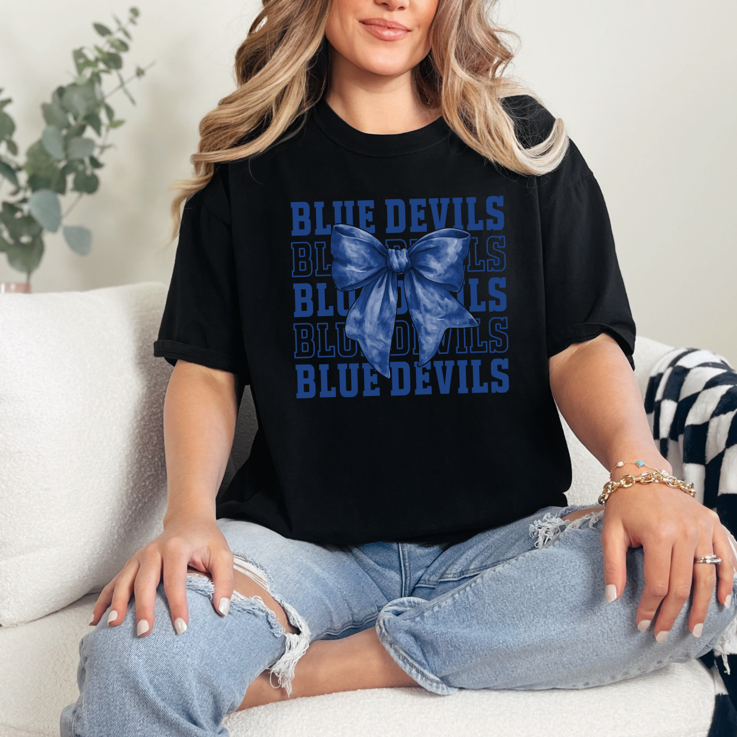 Woman wearing Tipton Blue Devils coquette bow spirit wear shirt with layered Blue Devils typography and blue bow graphic