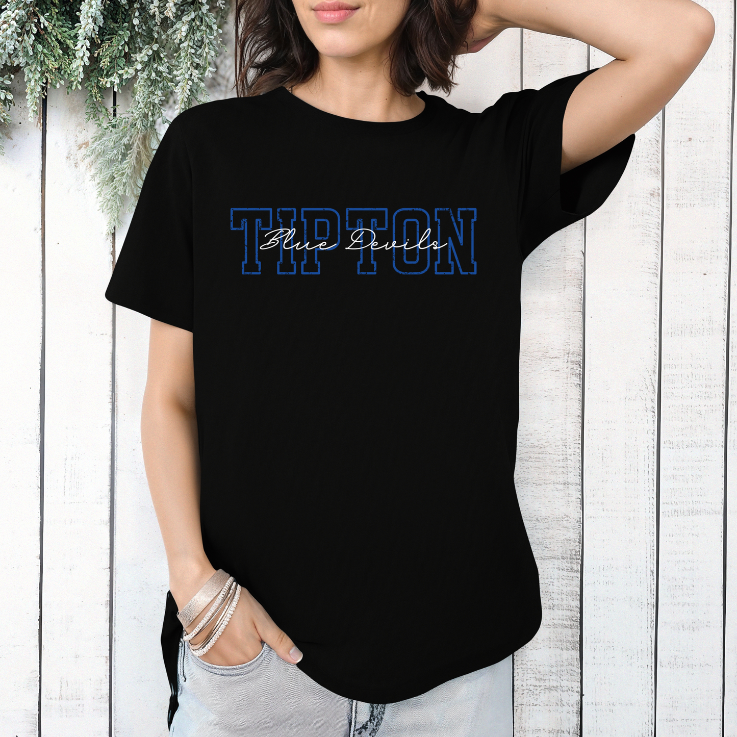 Woman wearing a black graphic t-shirt featuring a layered 'TIPTON' design with 'Blue Devils' in an elegant script font layered on top.