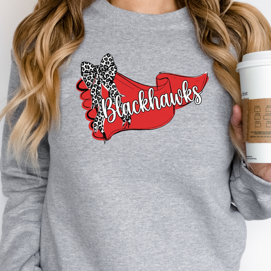 Woman holding a coffee cup, wearing a grey crewneck sweatshirt with a trendy Blackhawks team banner and leopard bow design.