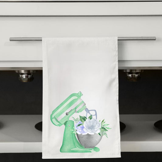 Kitchen towel with a mixer and flower design hanging on a cabinet handle.
