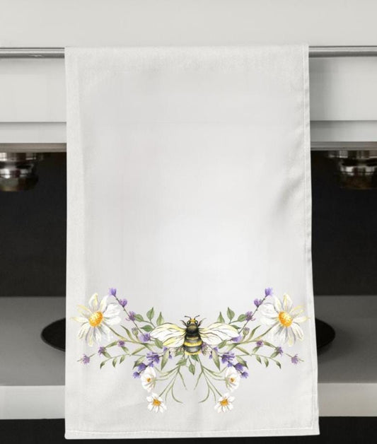White towel with a bee and floral design on a kitchen counter.