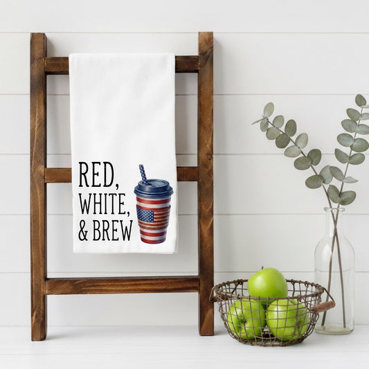 Wooden ladder with a towel featuring text and a cup graphic, next to a basket of apples and a vase with greenery on a white background.