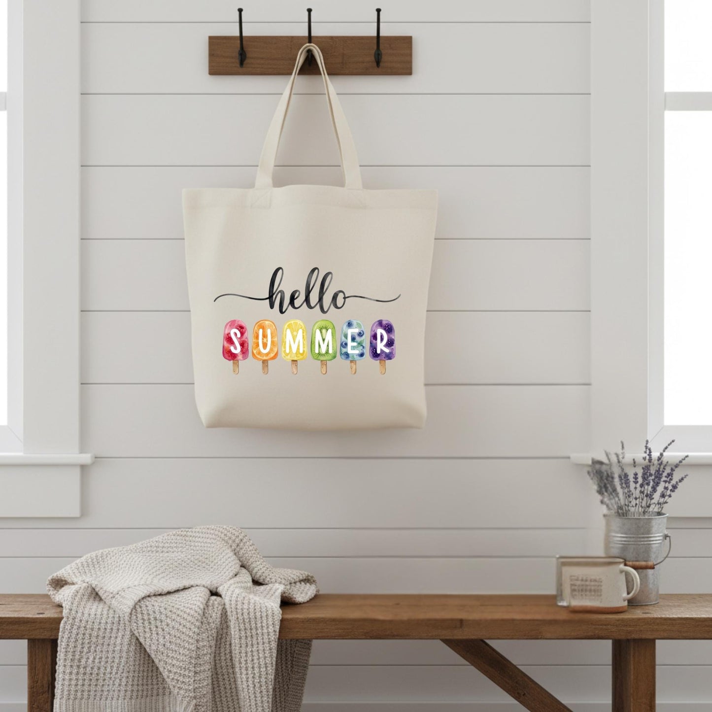 Tote bag with 'hello summer' text on a wooden bench against a white wall.