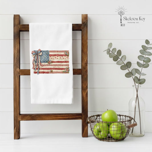 Patriotic farmhouse tea towel featuring vintage American flag design with flowers and rustic Americana decor