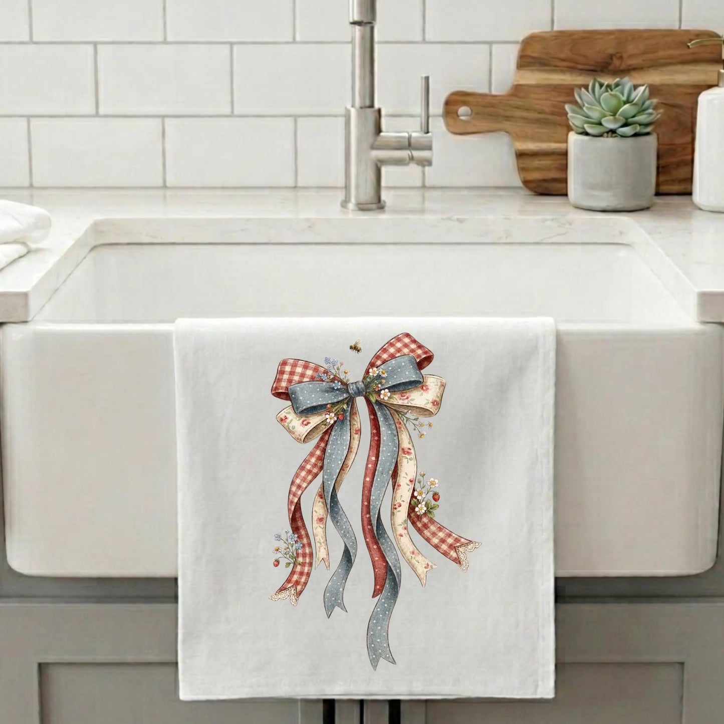 Americana tea towel with floral patriotic bow design hanging on farmhouse sink for Fourth of July decor