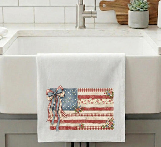 Vintage American flag kitchen towel with floral accents and patriotic ribbon displayed on farmhouse sink