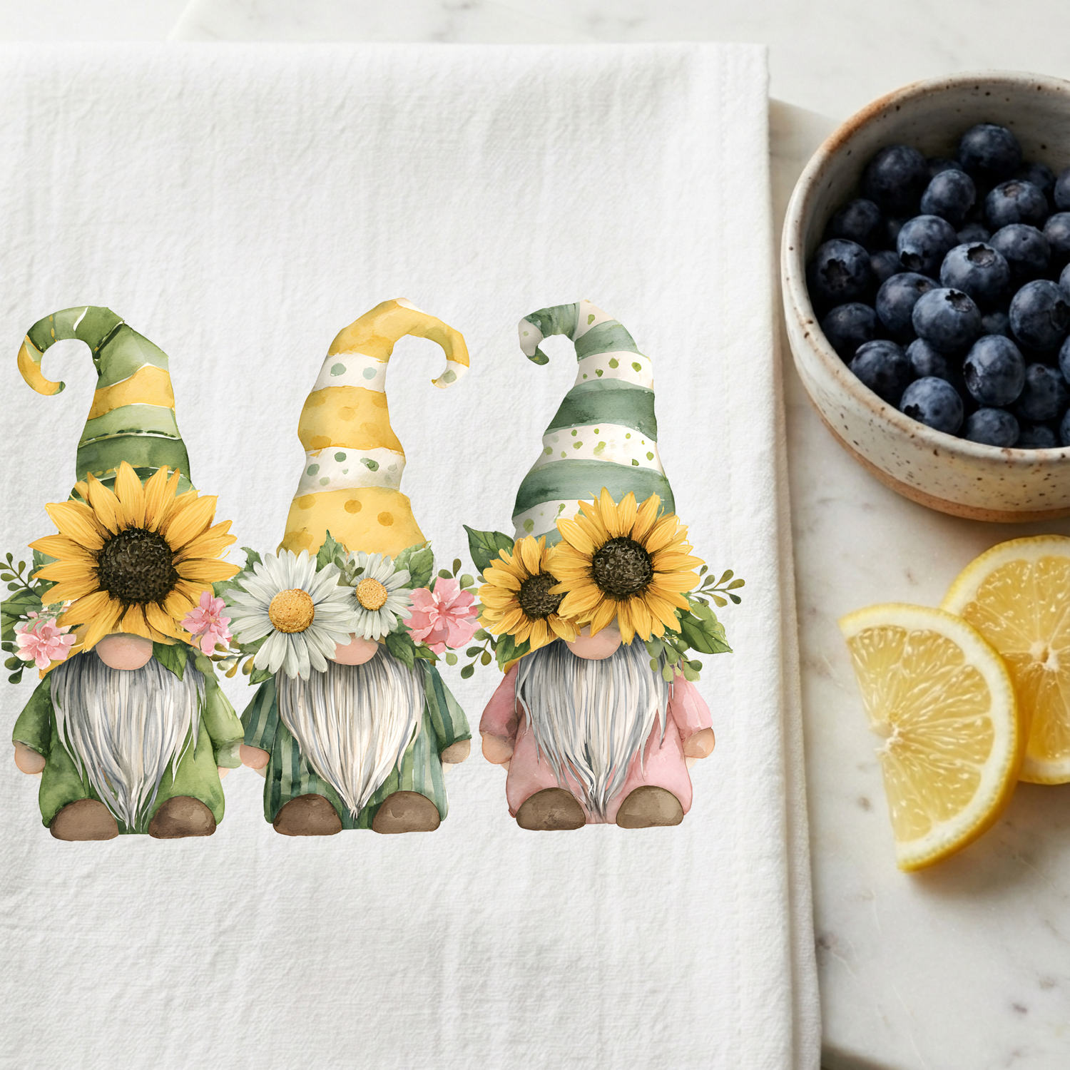 Sunflower gnome tea towel featuring three watercolor floral gnomes with sunflowers and daisies on a white kitchen towel