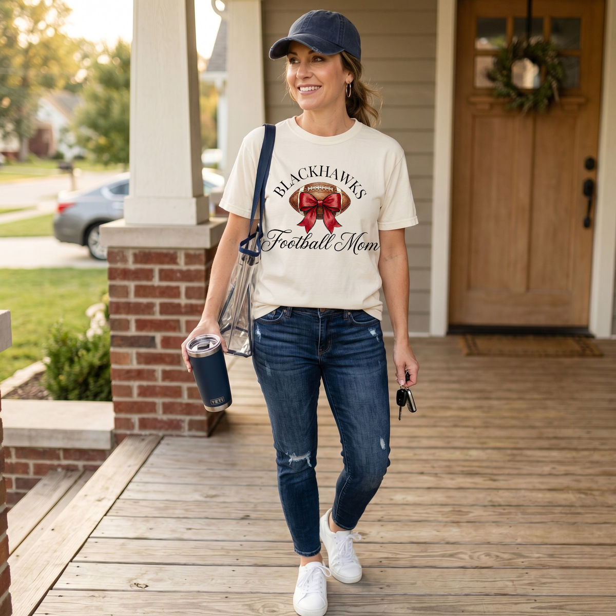 Sheridan Blackhawks Football Mom shirt featuring a watercolor football with red bow graphic on a white Comfort Colors tee