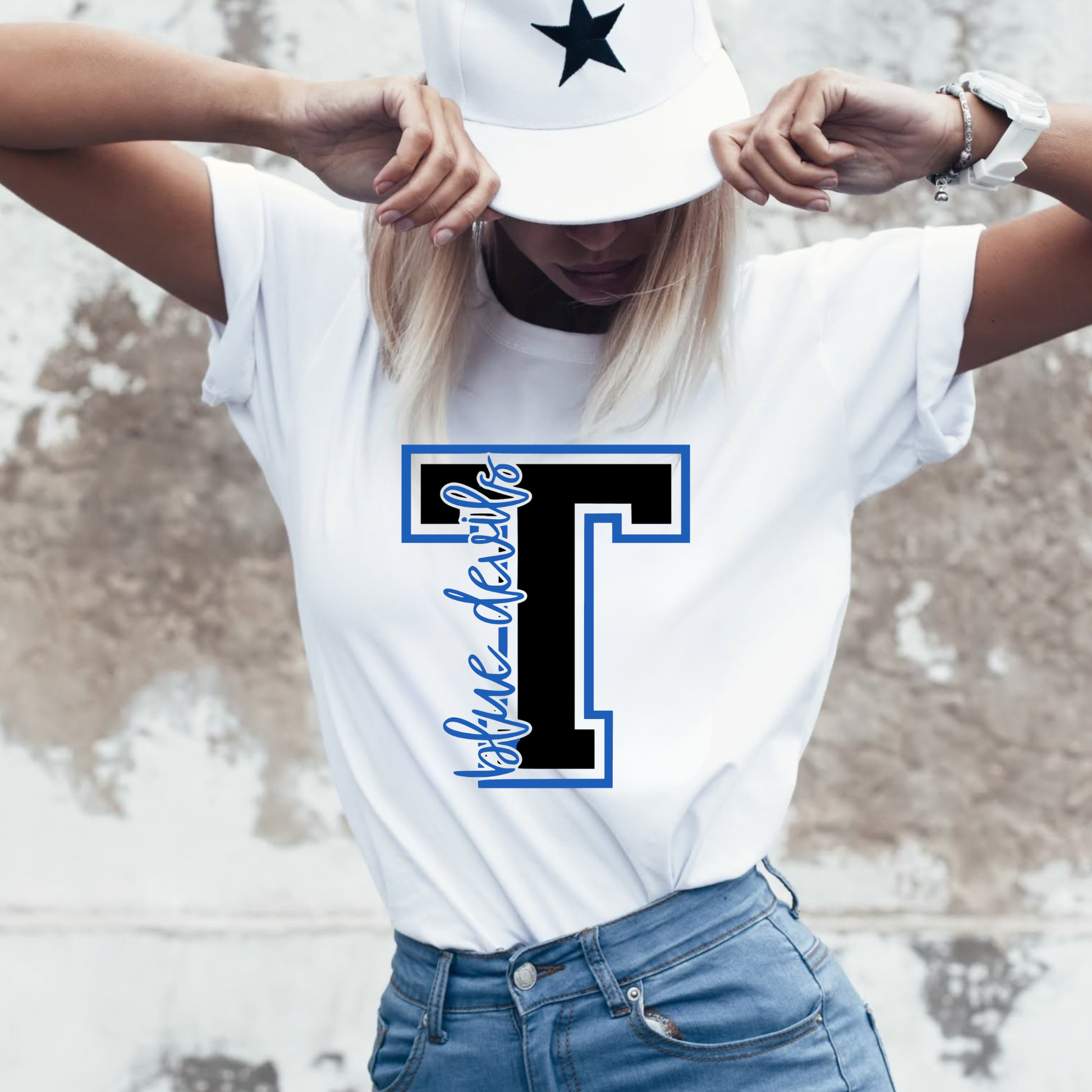 Woman wearing a white t-shirt with a large letter 'T' design, standing outdoors.