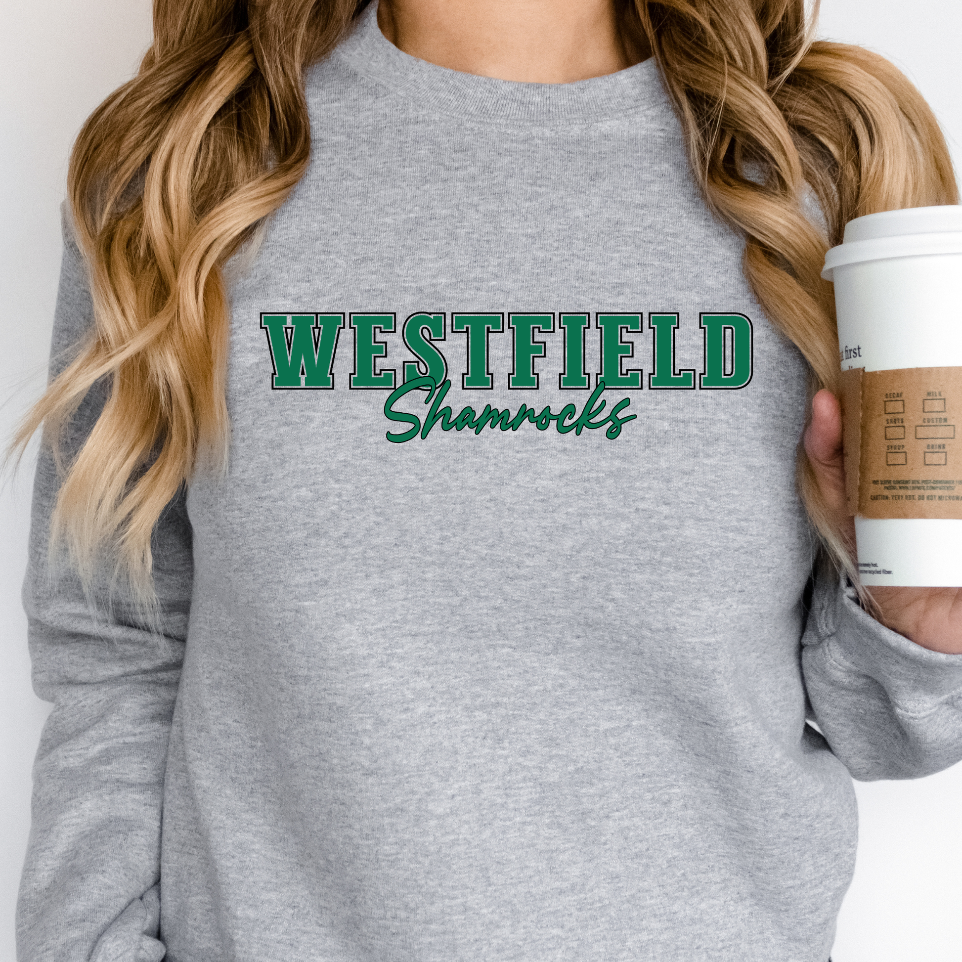 Person wearing a gray sweatshirt with 'Westfield Shamrocks' text, holding a coffee cup.