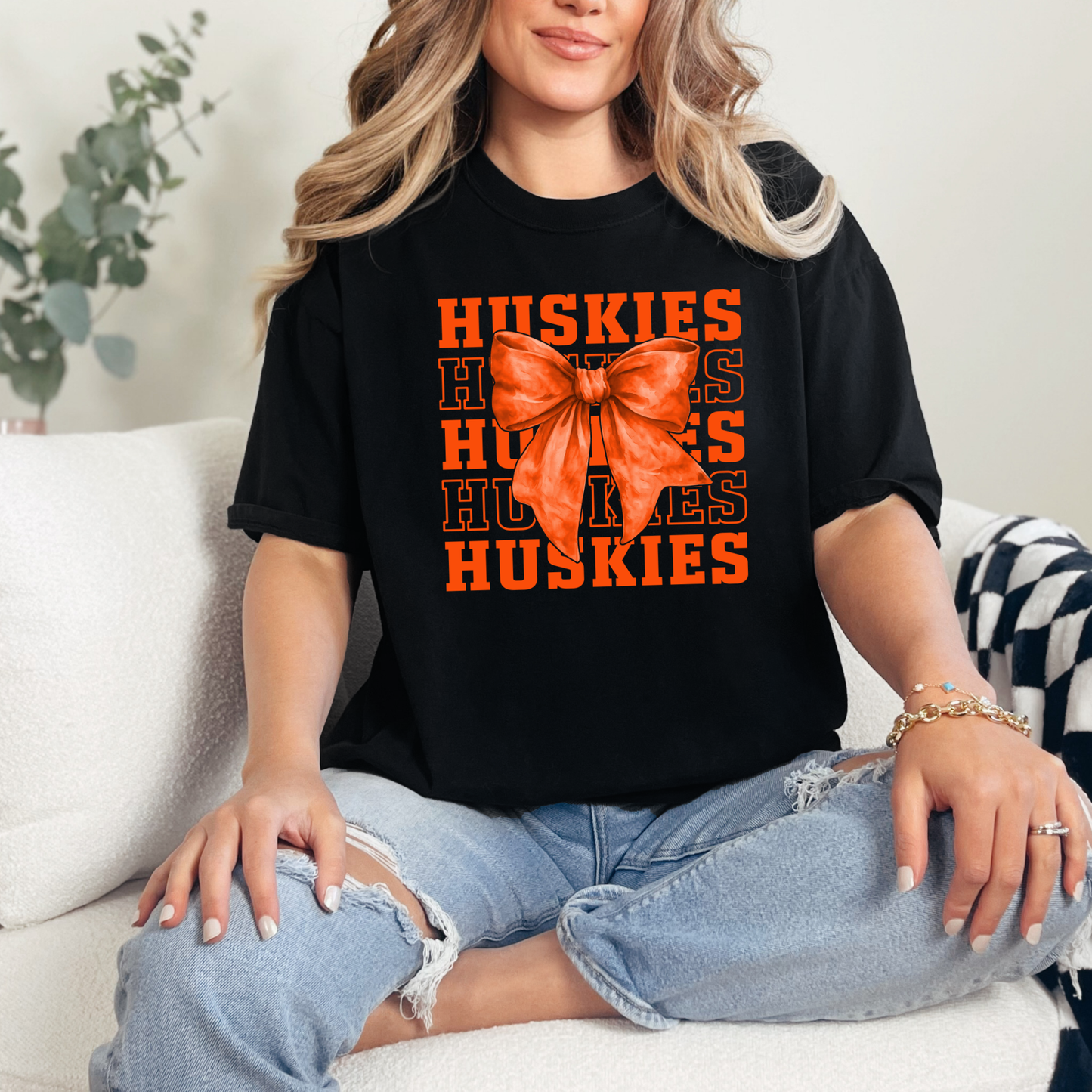 Woman wearing Hamilton Heights Huskies coquette bow spirit wear shirt with orange bow graphic and layered Huskies typography