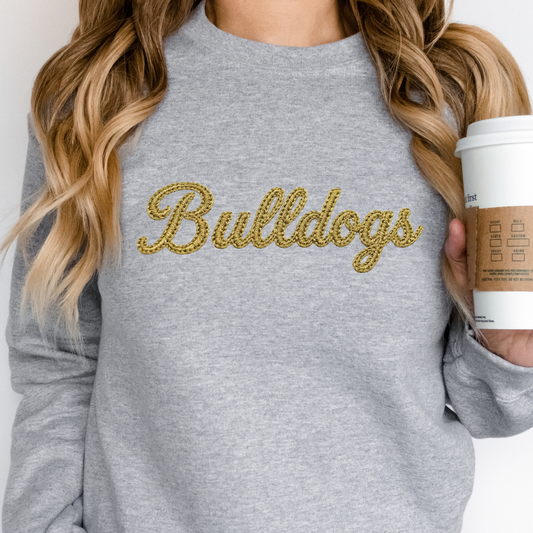 Woman wearing a grey Lapel Bulldogs Faux Embroidered Crewneck Sweatshirt featuring a gold faux embroidered Bulldogs script design for school spirit apparel.