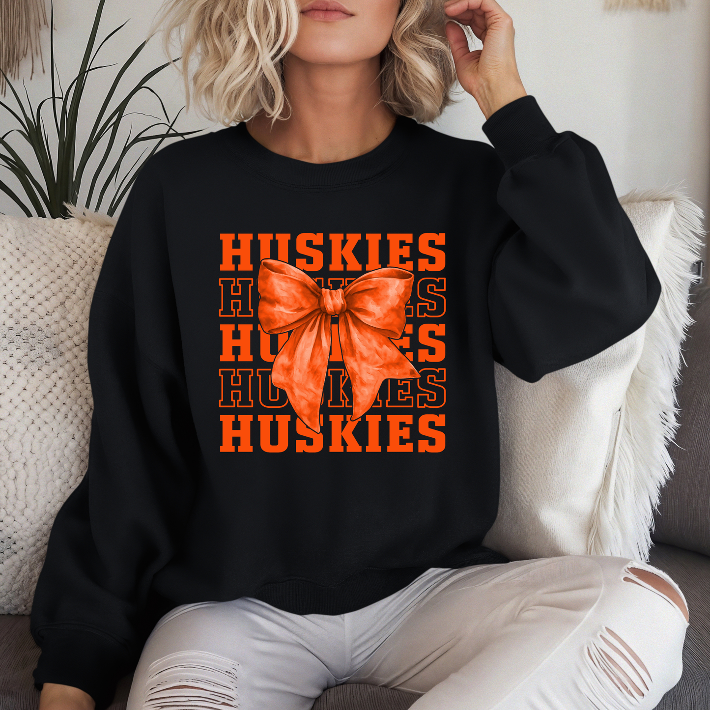 Woman wearing Hamilton Heights Huskies coquette bow spirit wear crewneck with layered Huskies typography and orange bow design