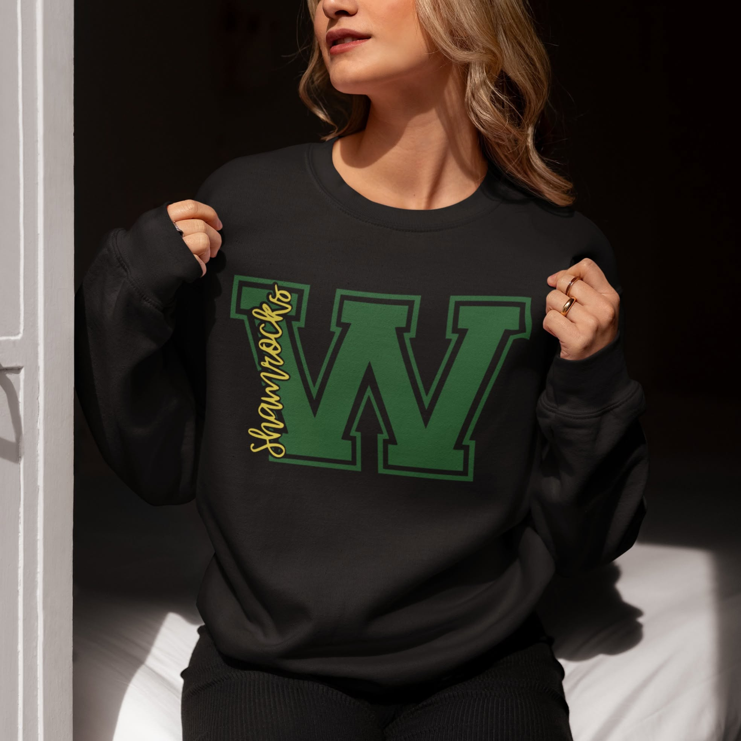 Woman wearing a Westfield Shamrocks Varsity W crewneck sweatshirt featuring green varsity letter W and Shamrocks script design on black sweatshirt