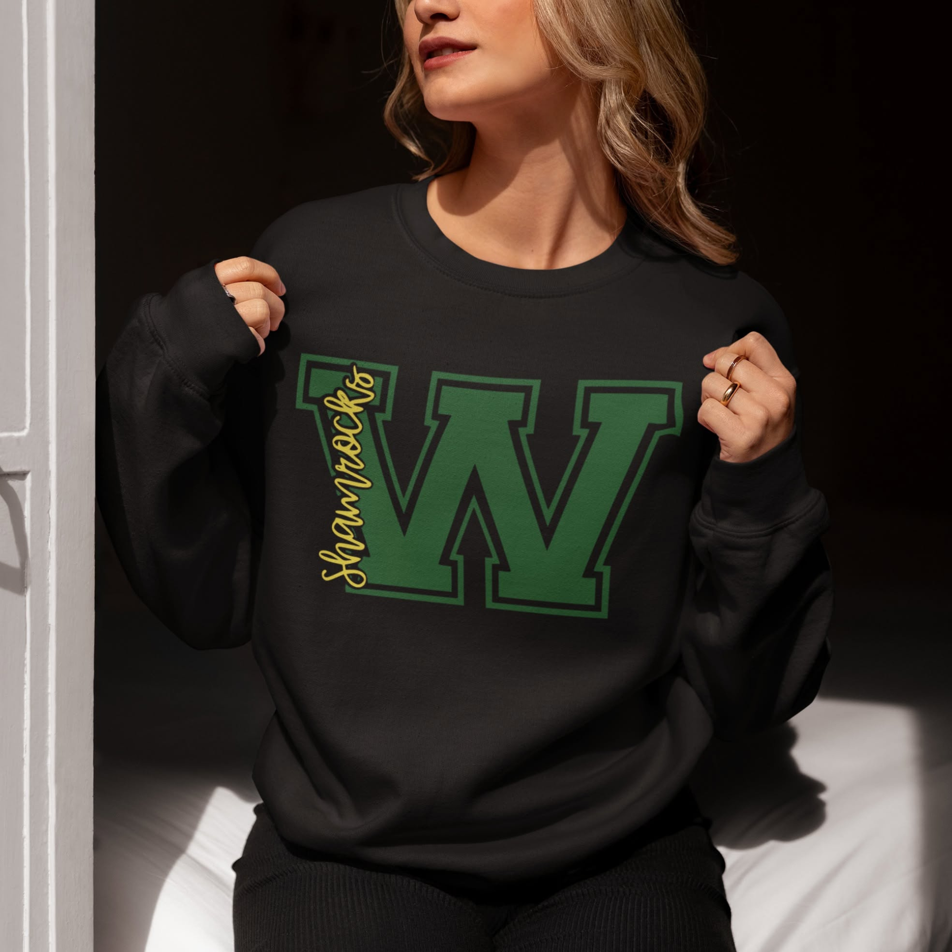 Woman wearing a Westfield Shamrocks Varsity W crewneck sweatshirt featuring green varsity letter W and Shamrocks script design on black sweatshirt