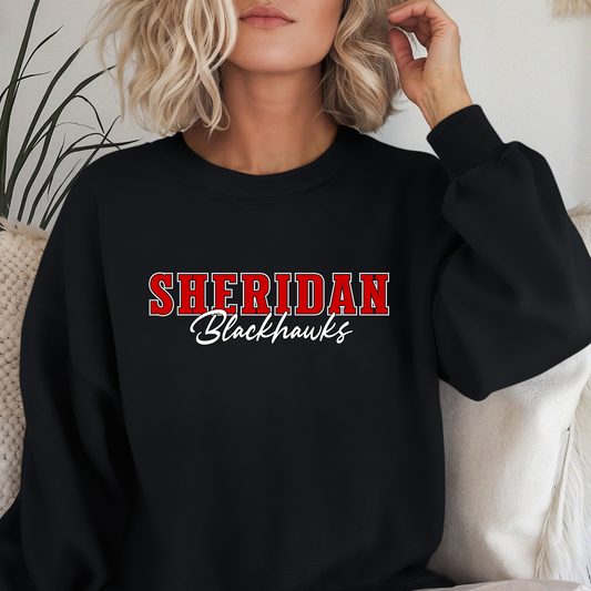 Woman wearing a Sheridan Blackhawks Script Spirit Shirt featuring bold red varsity Sheridan lettering with Blackhawks script design on a unisex crewneck sweatshirt.