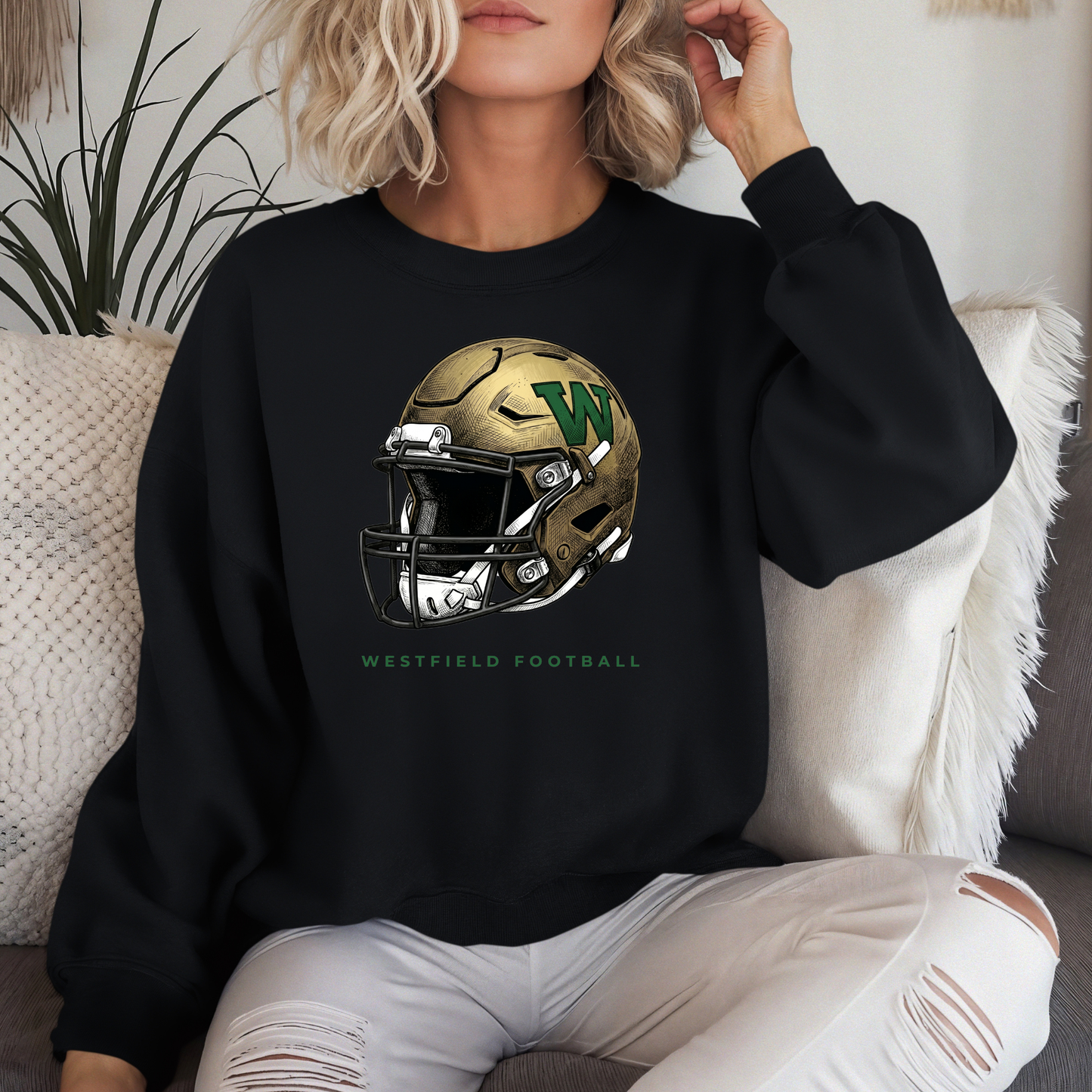 A person wearing a black crewneck sweatshirt featuring a gold and green Westfield football helmet design with the text 'WESTFIELD FOOTBALL'.