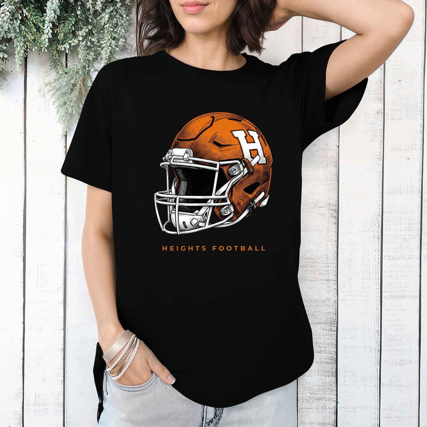 Woman wearing a black graphic t-shirt featuring an orange and white Hamilton Heights football helmet design with the text 'HEIGHTS FOOTBALL'.
