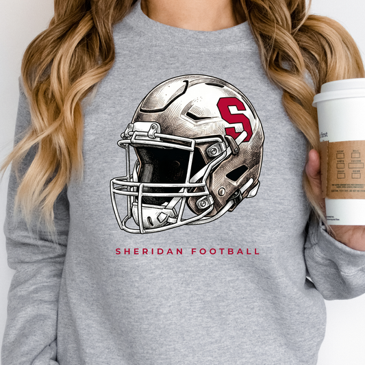 Woman holding a coffee cup, wearing a grey crewneck sweatshirt with a refined Sheridan Blackhawks football helmet illustration.