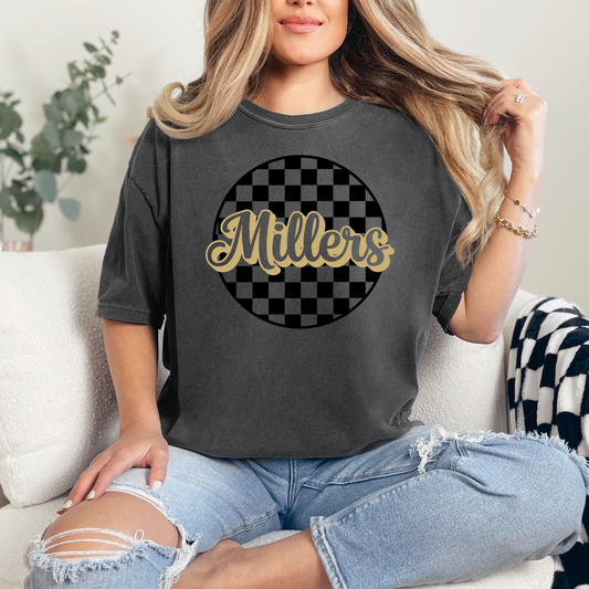 Woman wearing a dark gray t-shirt with 'Millers' design, sitting on a couch.