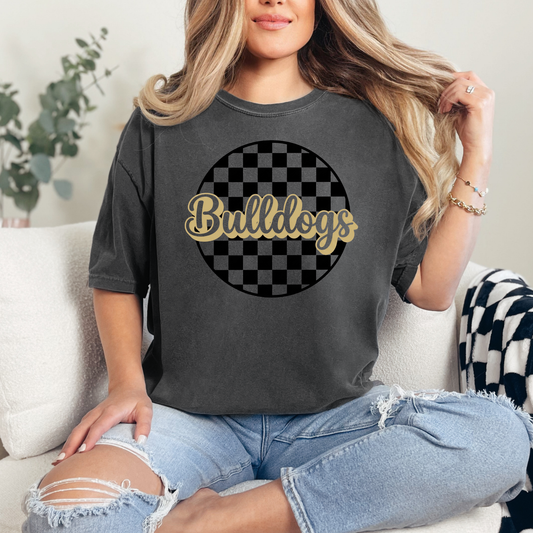 Person wearing a dark gray t-shirt with 'Bulldogs' text and checkered design, sitting on a couch.