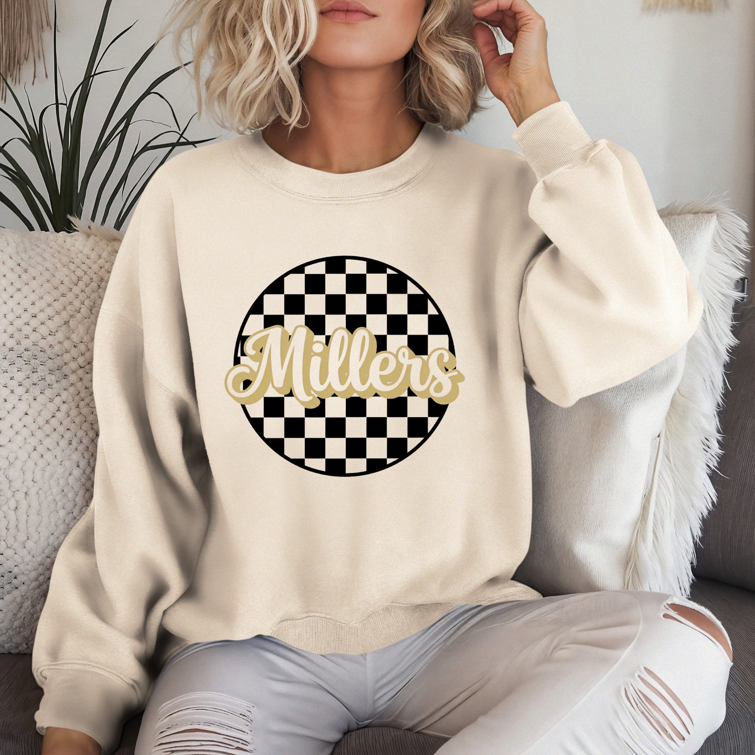 Person wearing a beige sweatshirt with 'Millers' graphic design.