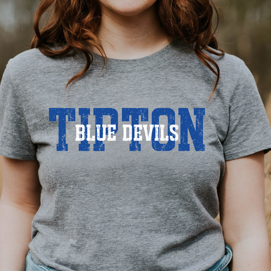 Woman wearing a grey graphic t-shirt featuring a layered 'TIPTON BLUE DEVILS' design with bold lettering.
