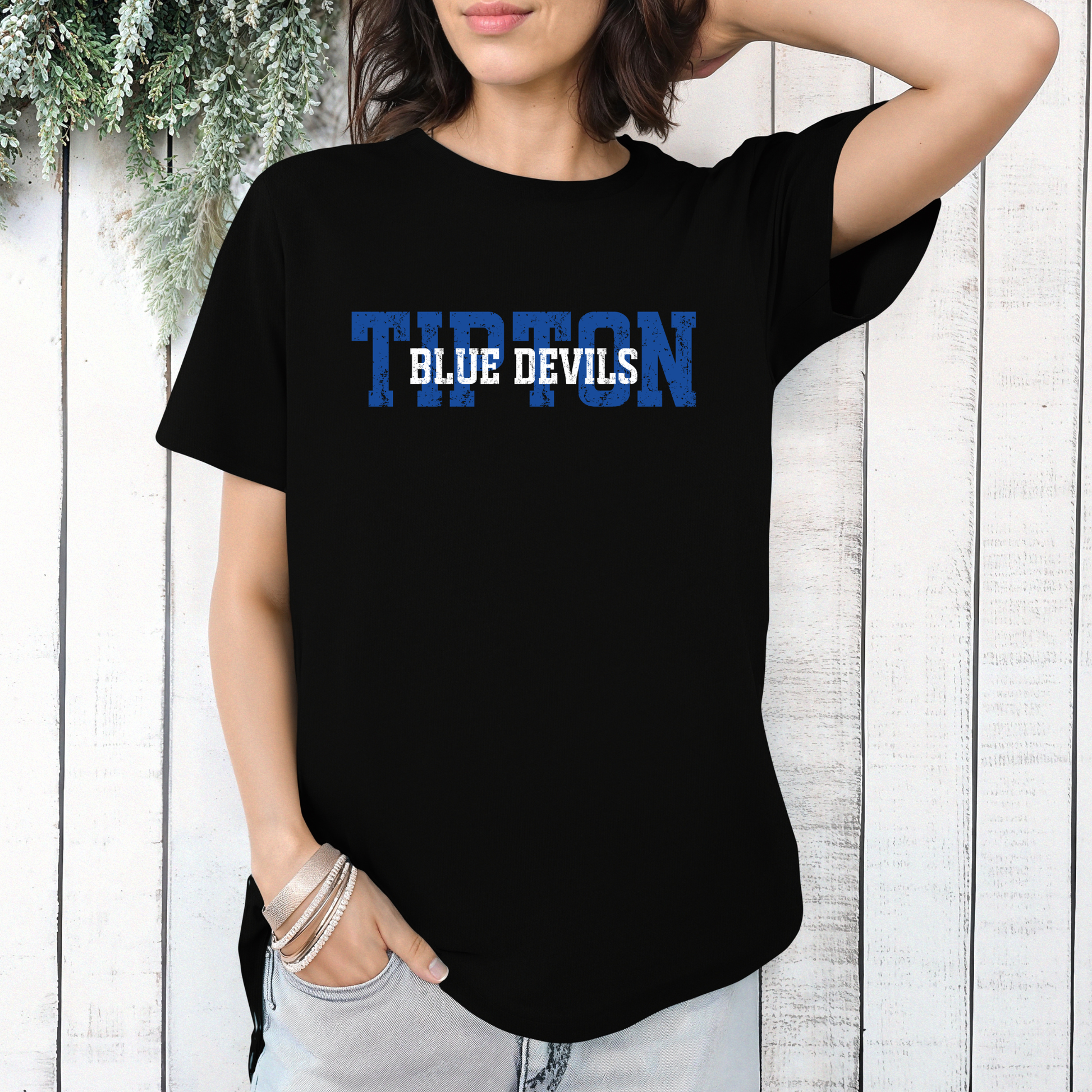 Woman wearing a black graphic t-shirt featuring a layered 'TIPTON BLUE DEVILS' design with bold lettering.