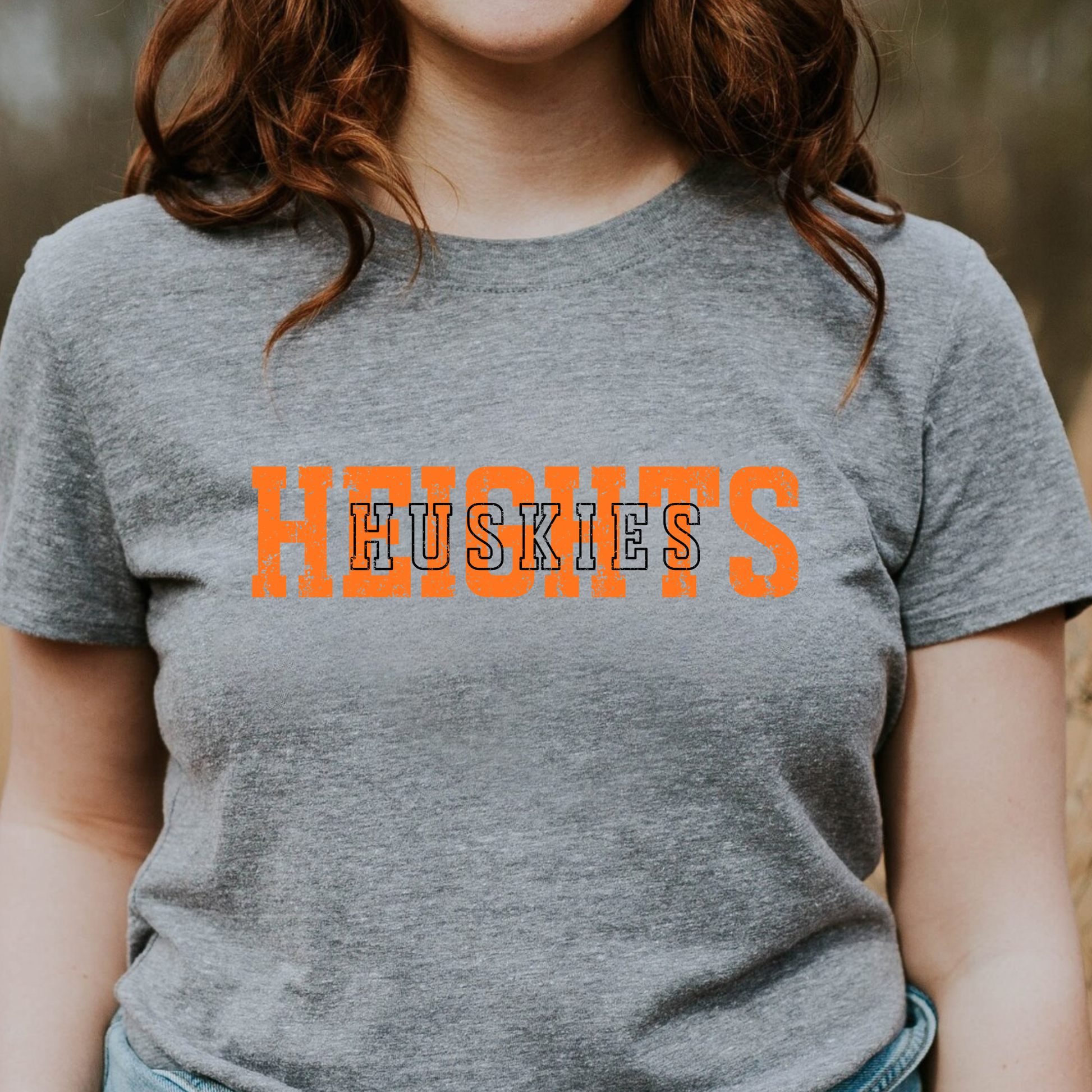 Person wearing a grey t-shirt with a distressed orange 'HEIGHTS' design and white 'HUSKIES' text layered on top.