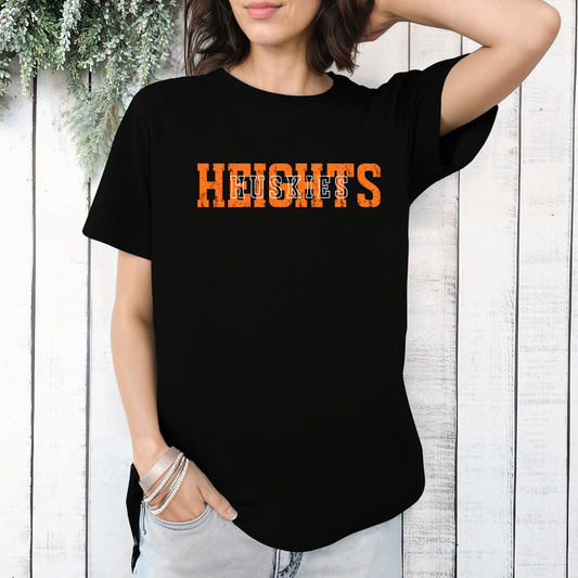 Person wearing a black t-shirt with a distressed orange 'HEIGHTS' design and white block-letter 'HUSKIES' text layered on top.