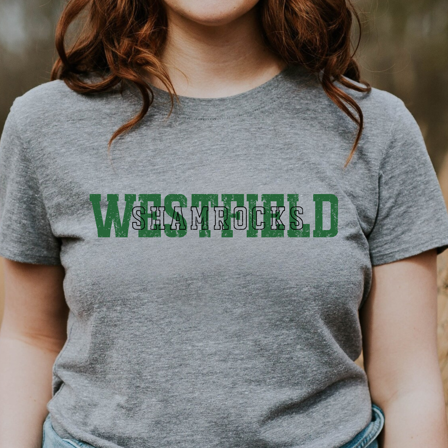 A person wearing a grey t-shirt featuring 'WESTFIELD' in large green block letters with 'SHAMROCKS' layered in a black-outlined font across the center.