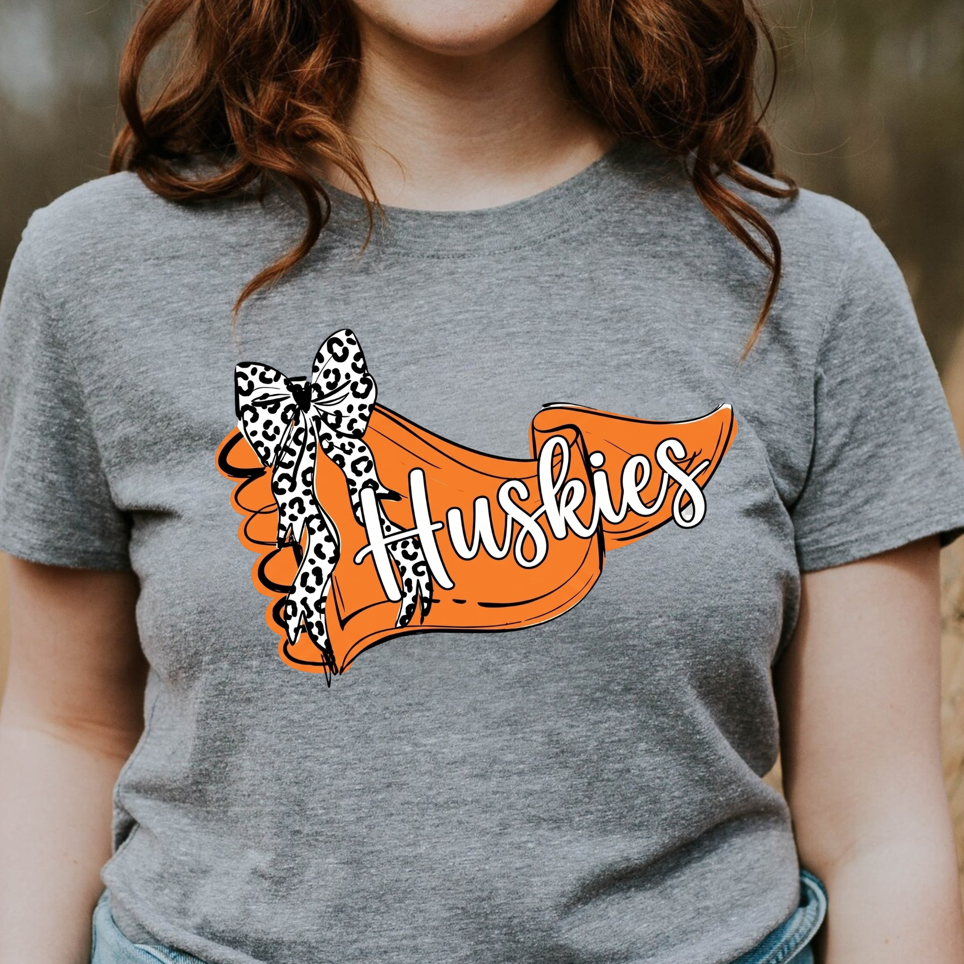 A close-up graphic showing an orange banner with 'Huskies' text and a leopard-print bow accent.