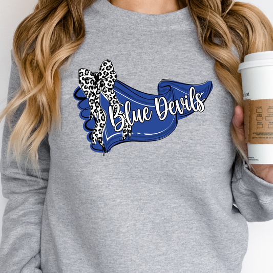Woman holding a coffee cup, wearing a grey crewneck sweatshirt featuring a blue 'Blue Devils' banner design with a leopard-print bow.