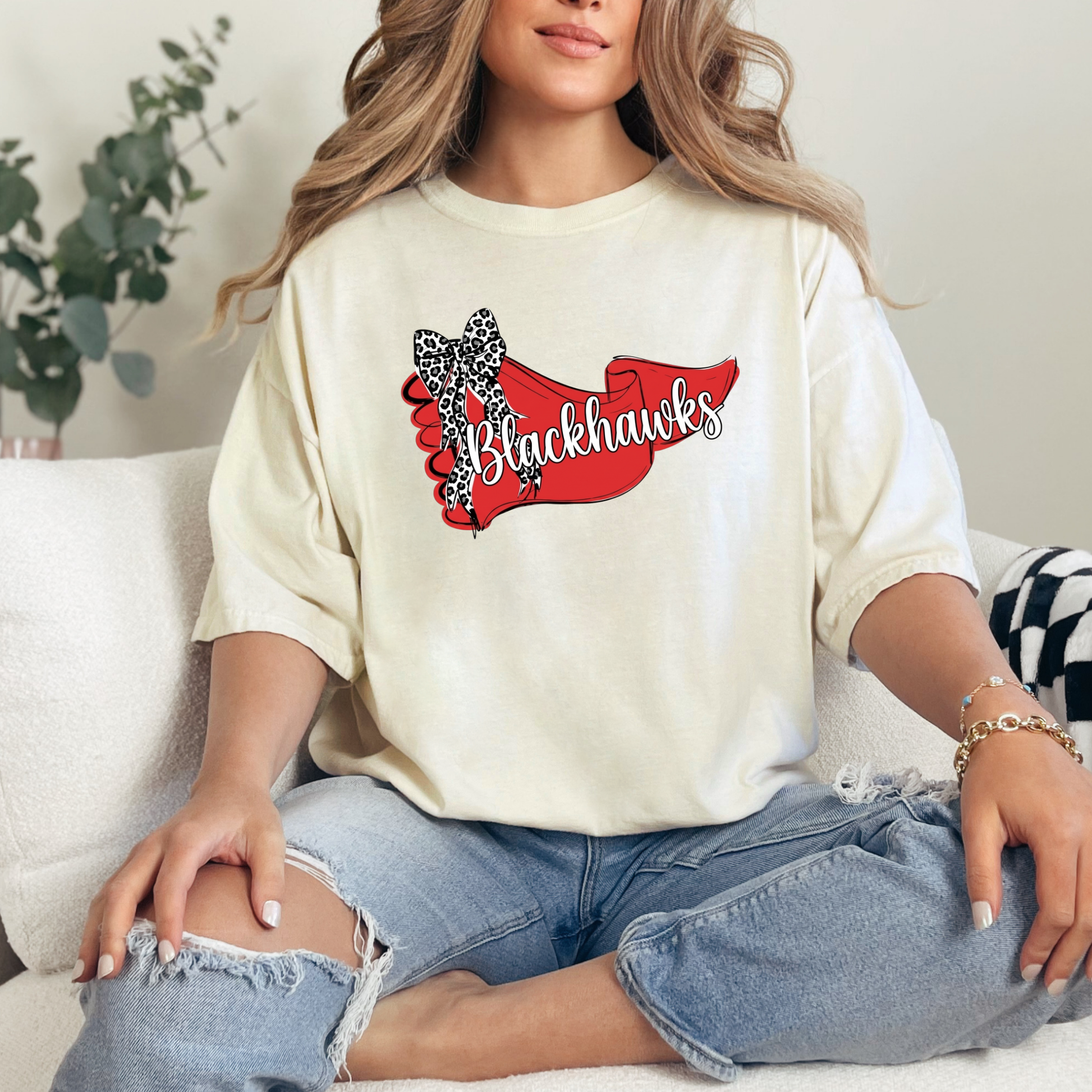 Woman in a cream-colored t-shirt with a stylish Blackhawks banner and animal-print bow graphic.