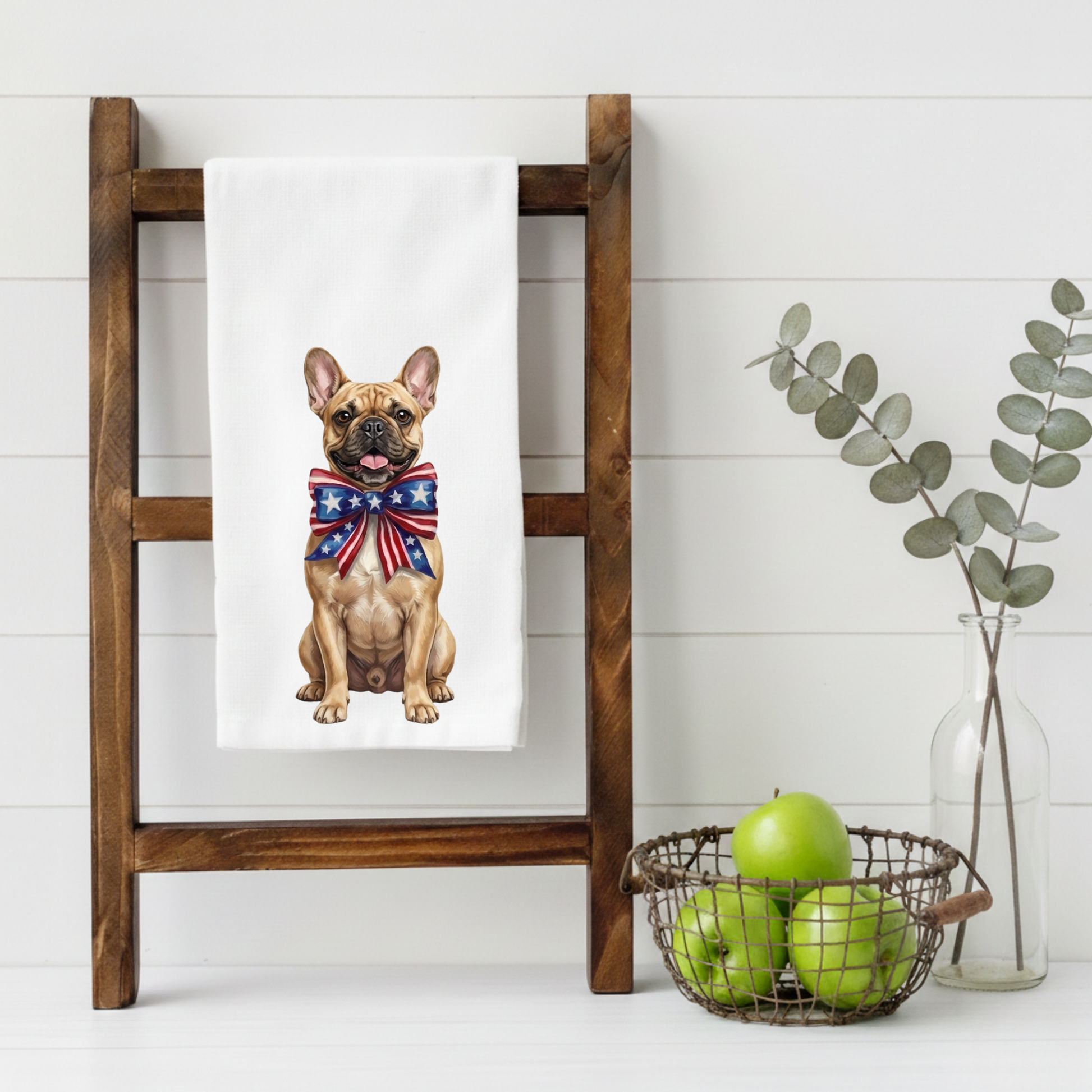 Towel with a French Bulldog wearing a Union Jack bow tie on a wooden ladder, with a basket of apples and a vase in the background.