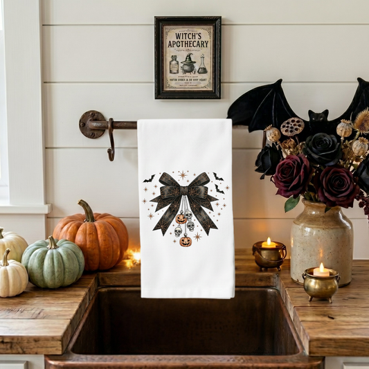Gothic coquette Halloween kitchen towel featuring black lace bow with skull charms, pumpkin ornaments, bats, and vintage spooky decor artwork