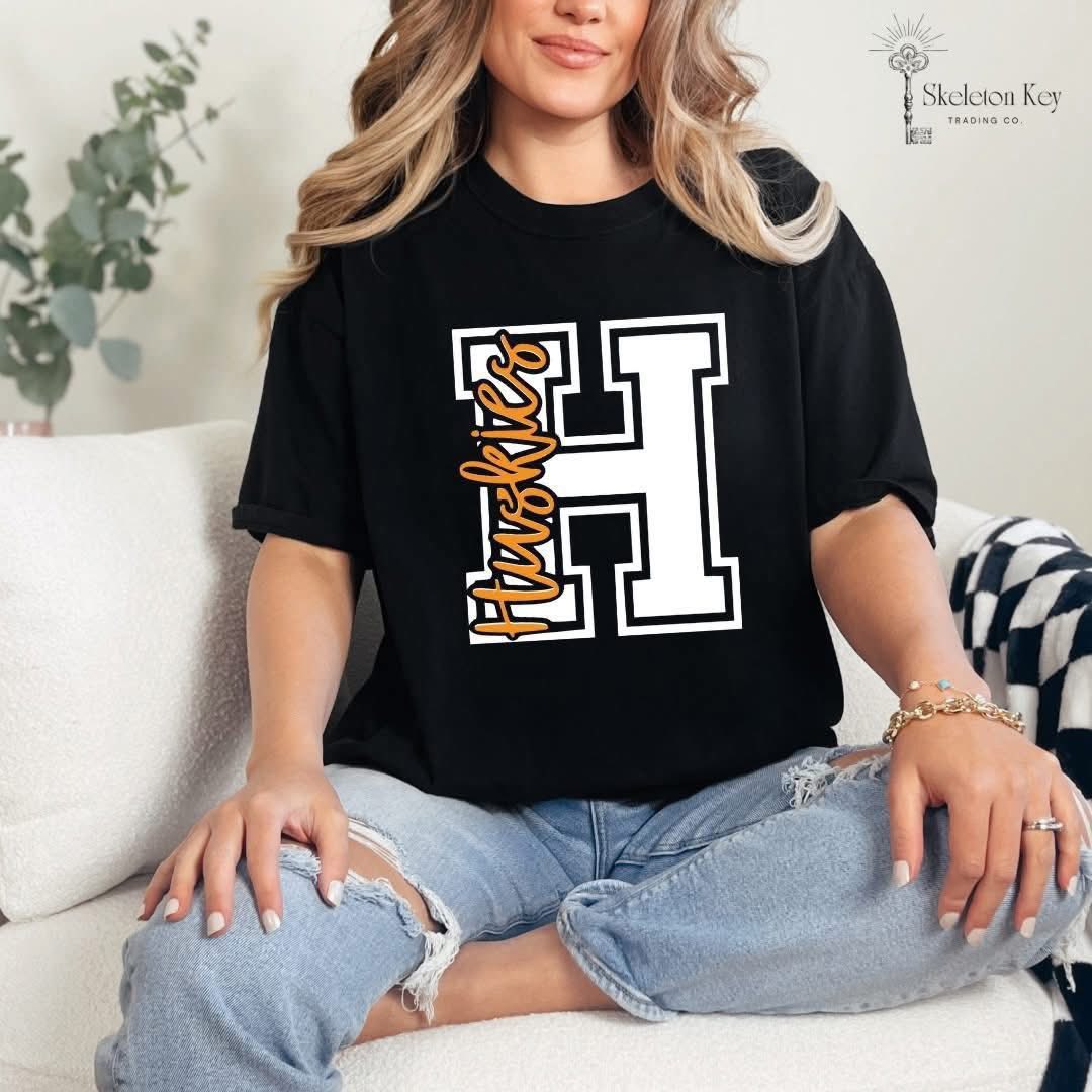 Woman wearing a Hamilton Heights Huskies Varsity H Comfort Colors tee in white and black.