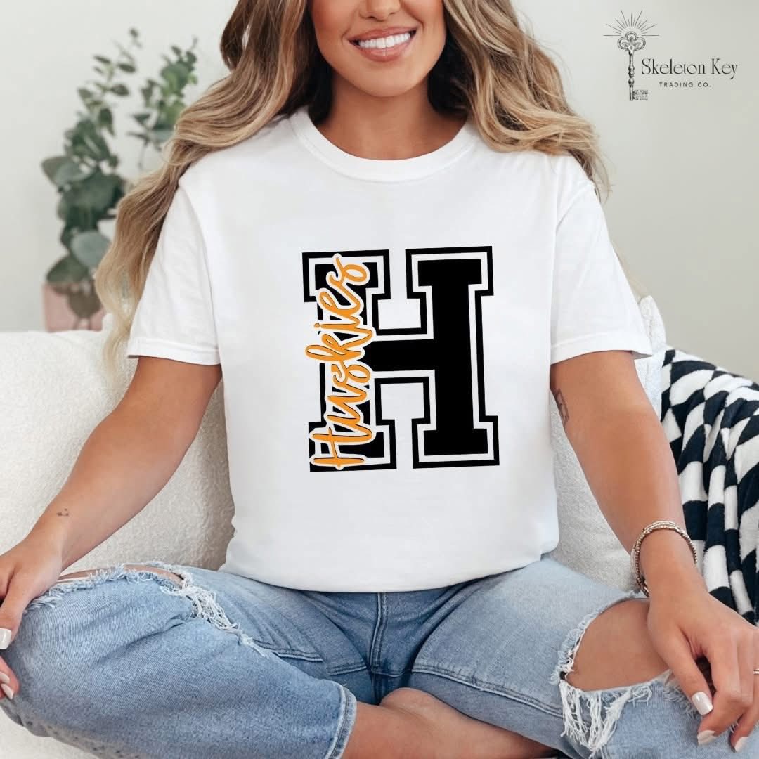 Woman wearing a Hamilton Heights Huskies Varsity H Comfort Colors tee in white and black.