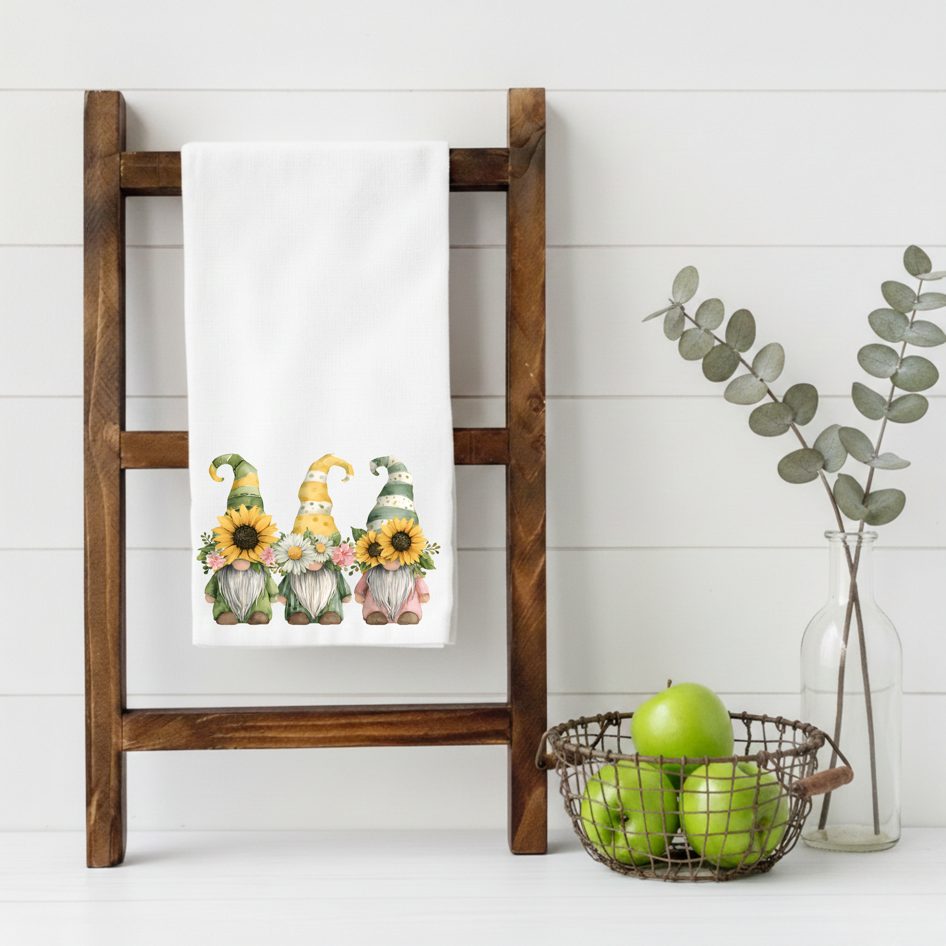 Watercolor sunflower and daisy gnome tea towel displayed on a wooden towel ladder in a farmhouse kitchen