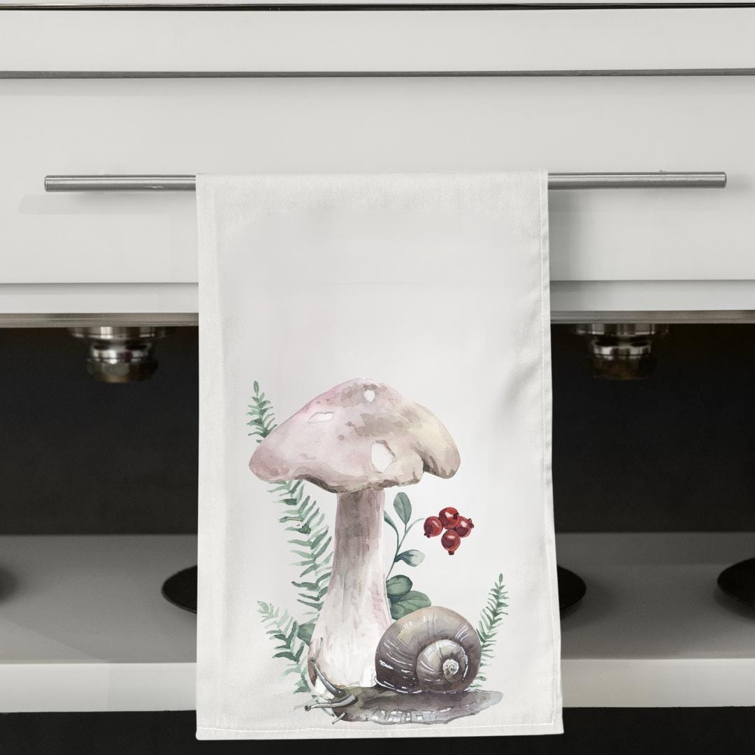 Kitchen towel with a mushroom design hanging on a cabinet handle.