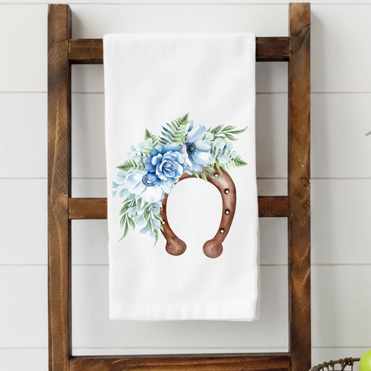 Floral towel with horseshoe design on a wooden ladder against a white wall.