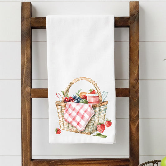 White towel with a picnic basket design hanging on a wooden rack.