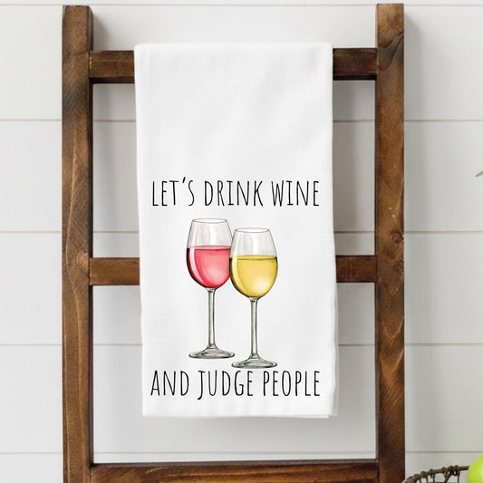 White towel with wine glass design and text on a wooden ladder against a white wall.