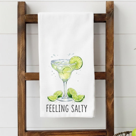 Towel with a margarita graphic and 'Feeling Salty' text on a wooden rack.