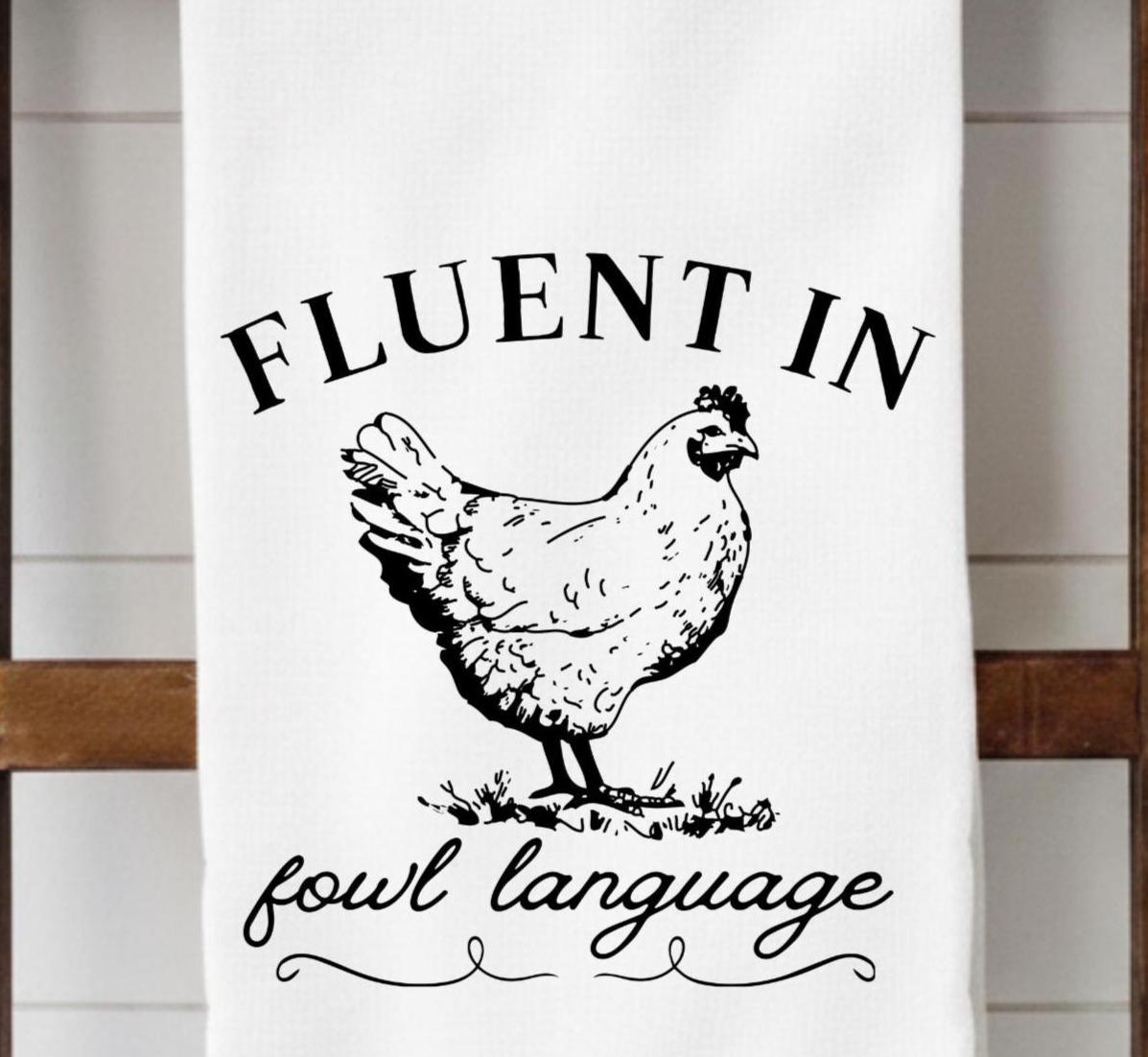 White towel with black text and chicken illustration on a wooden surface