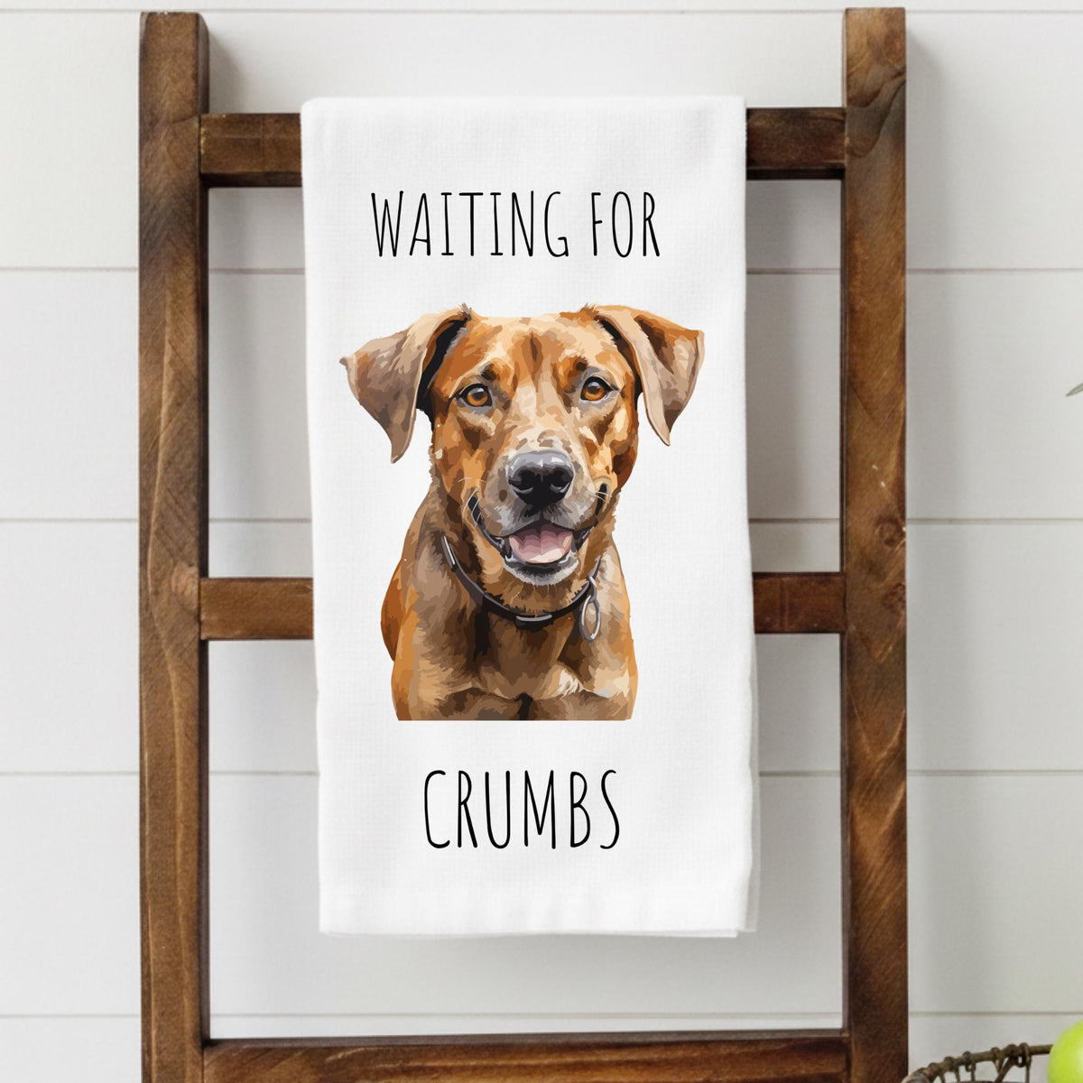 Tea towel with a dog illustration and text 'Waiting for Crumbs' on a wooden ladder.