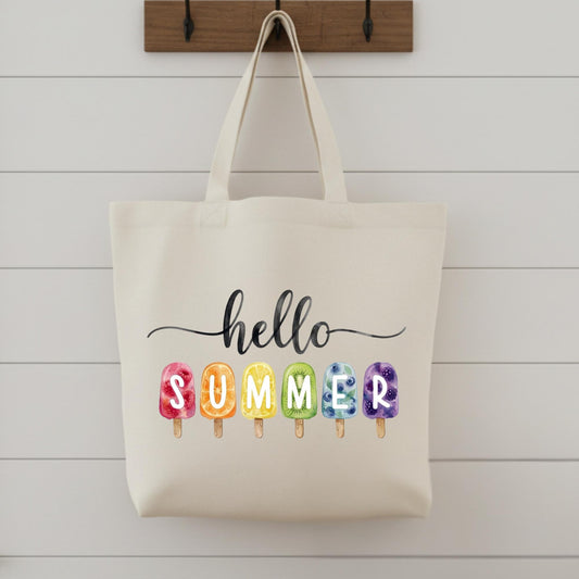 Beige tote bag with 'hello summer' text and colorful ice cream cone illustrations on a wooden surface.