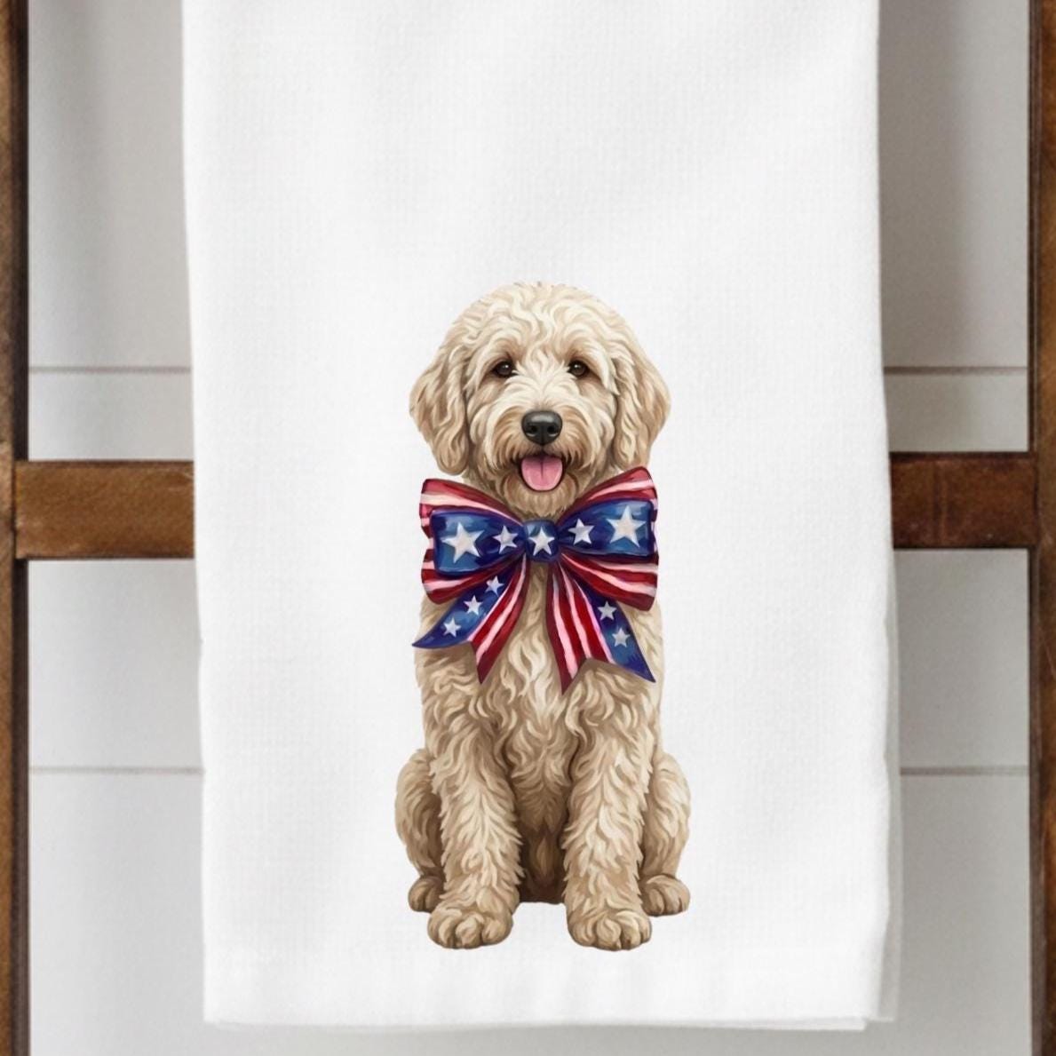 Flour sack towel hanging on a ladder display with an illustration of a golden Labradoodle wearing a patriotic bow