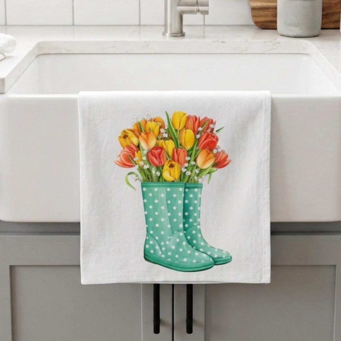 Towel with a design of green wellington boots with white polka dots and colorful tulips hanging on a kitchen towel rack.